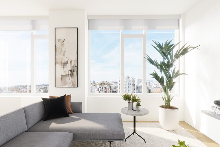 A living area featuring a couch, a small side table, some art, and a large houseplant.