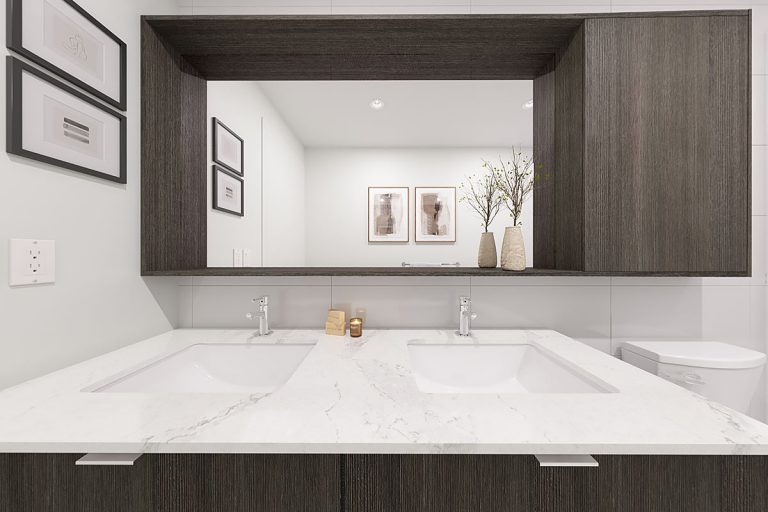 A bathroom, featuring two double sinks and a mirror